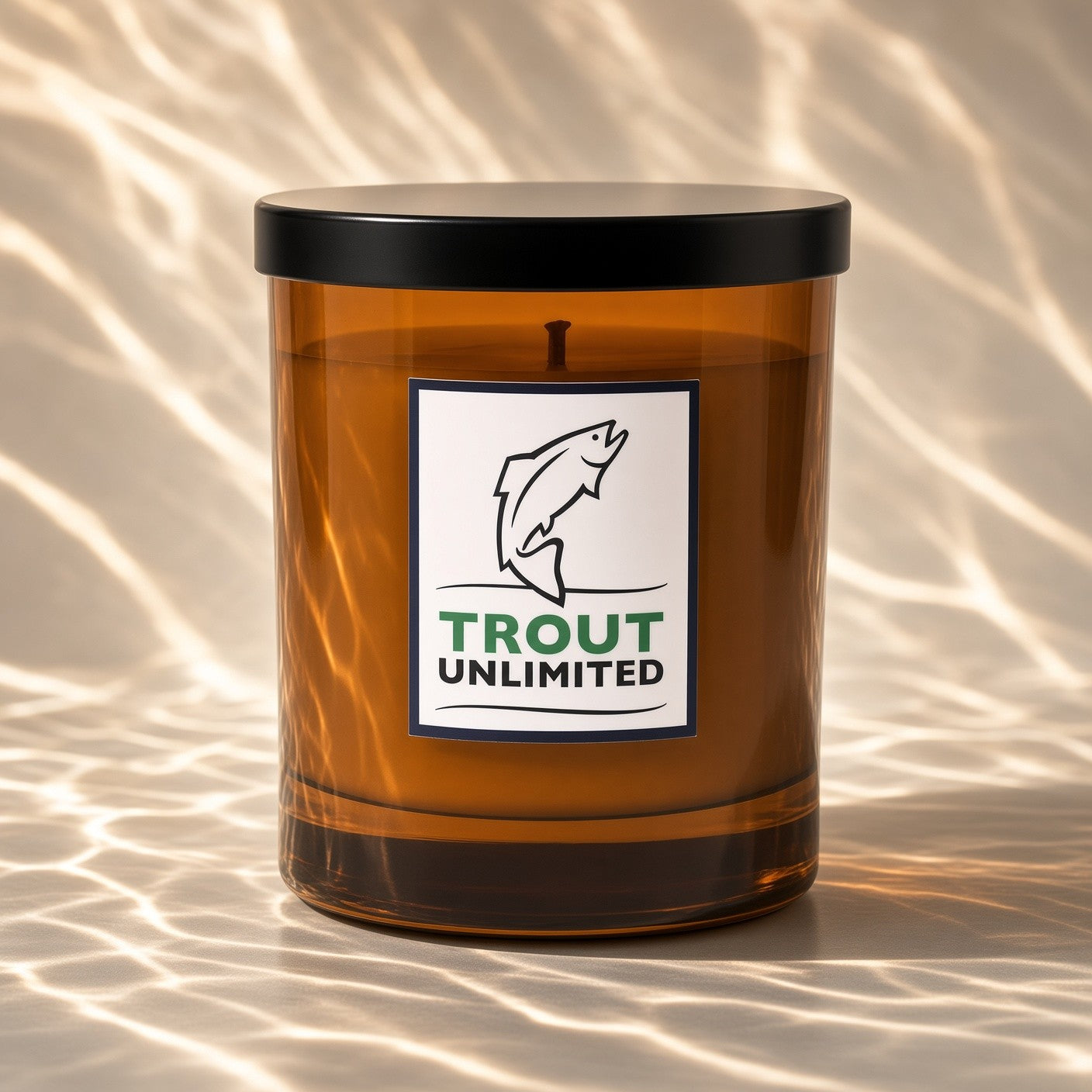 AURA Candle Bar X Trout Unlimited Western Mend Fragranced Candle in an amber glass vessel with a black lid.  Shimmering water shadow surround the candle vessel